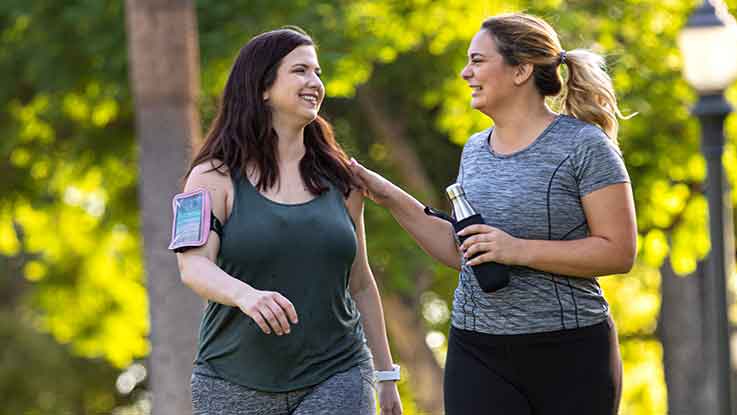 Two women share a laugh during an outdoor run together.