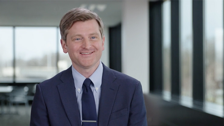 A business smiles as he speaks to the camera.