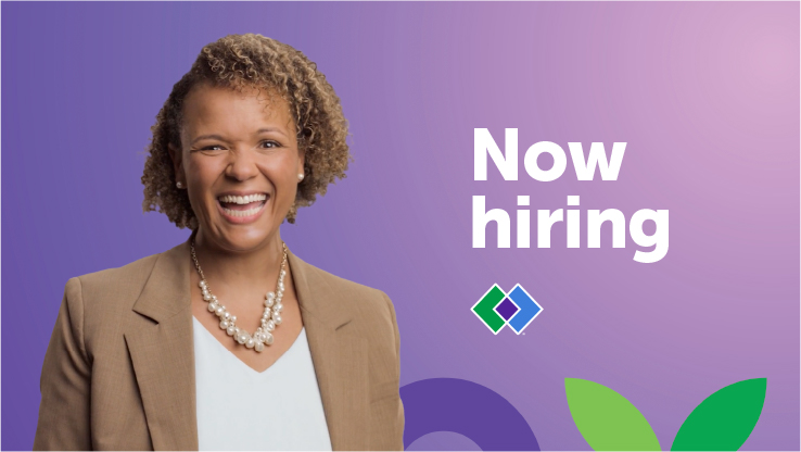 A black woman smiles in front of the words "now hiring."