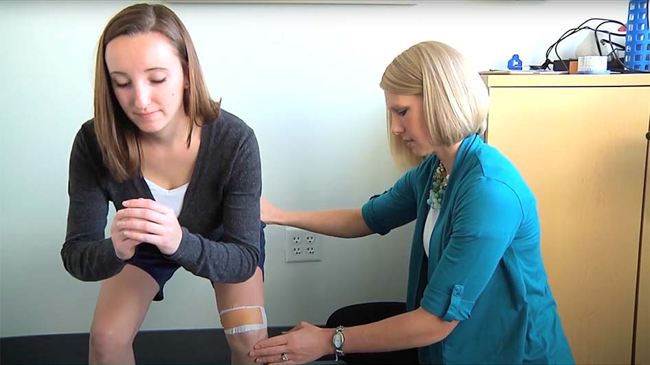 Physical therapist Rachel Hakanson guides a female patient through a knee exercise.