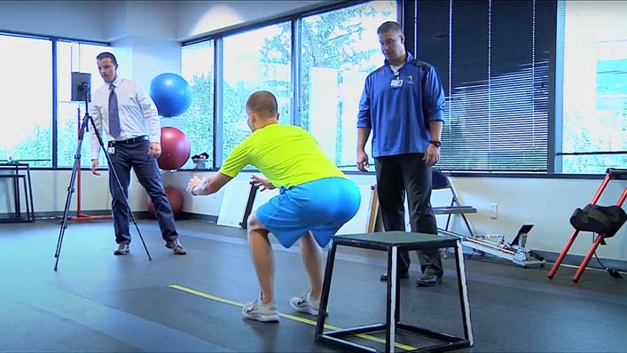 Physical therapists film a male patient jumping as part of a video analysis.